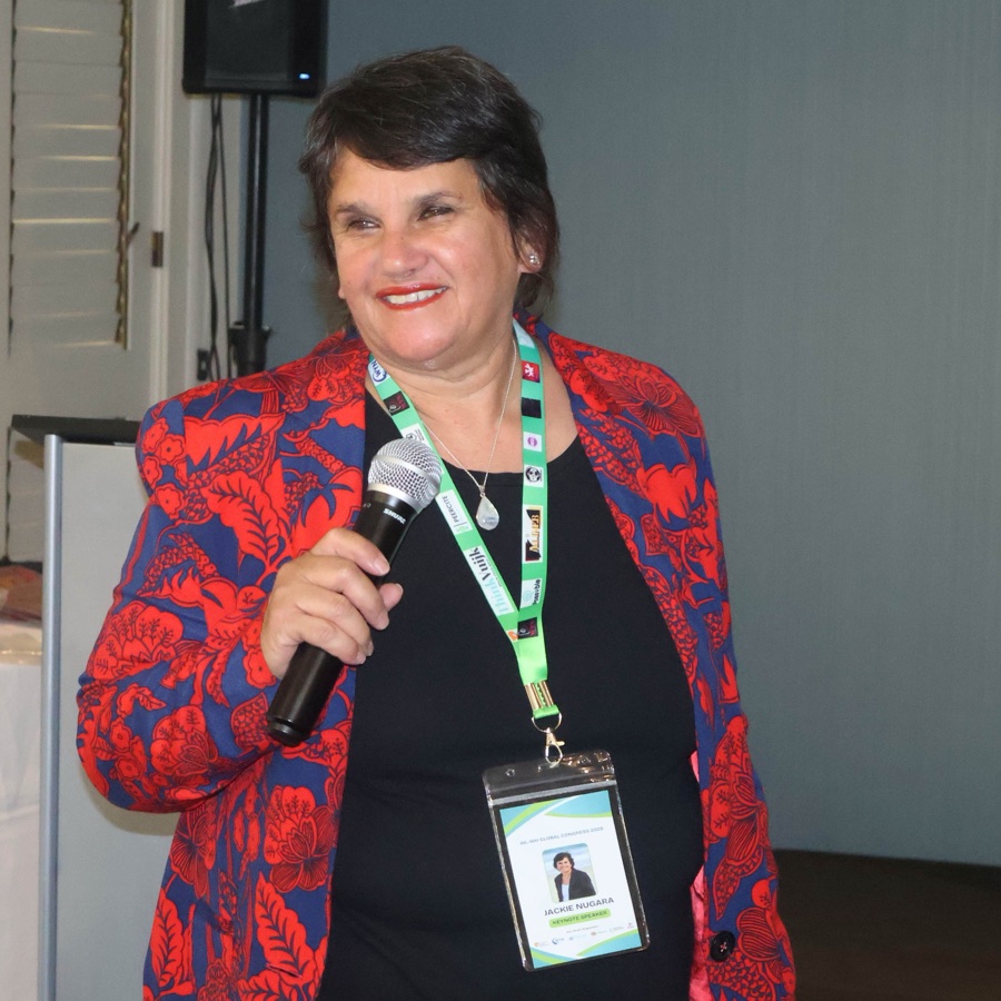 Jackie Nugara speaking with a microphone as keynote speaker at a conference